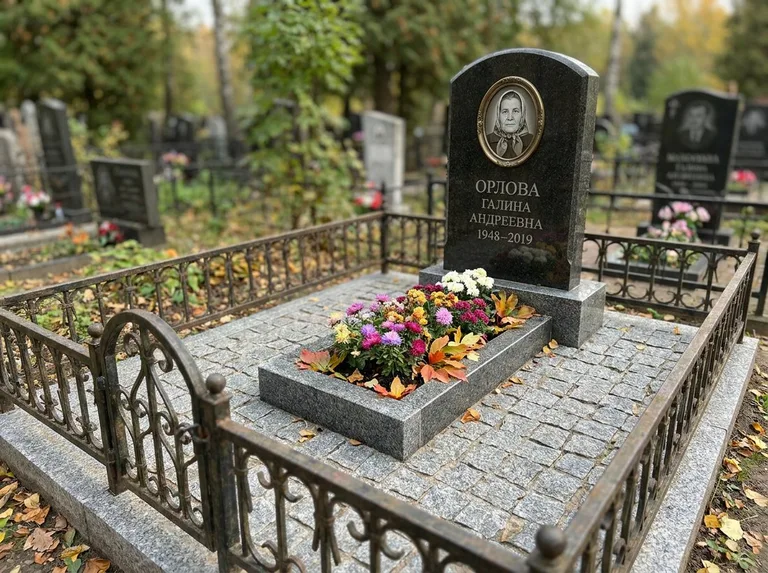 Благоустроенное захоронение с гранитной плиткой, оградой и цветником в Санкт-Петербурге