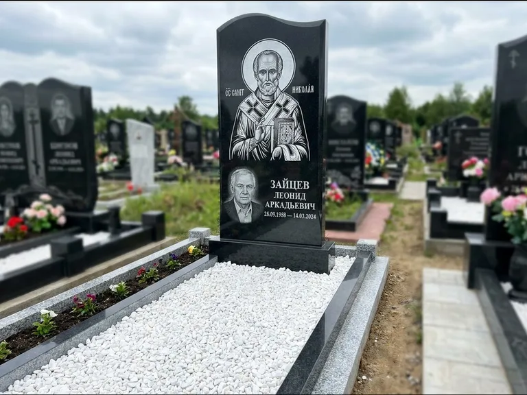 Памятник с гравировкой иконы: стела с крестообразным навершием — икона в резной рамке-киоте, газон без ограды, стриженая трава, работа «Раевская» в Санкт-Петербурге