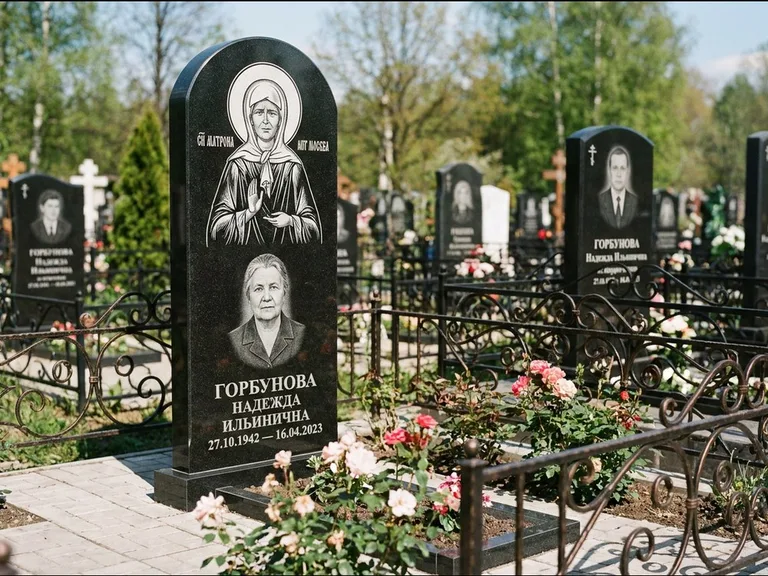 Памятник с гравировкой иконы: стела с арочным верхом и киотом под образ — гравировка образа Матроны Московской, гранитный цоколь с тёмной плиткой, работа «Ковалёв» в Санкт-Петербурге
