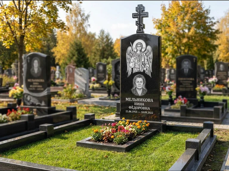 Памятник с гравировкой иконы: округлая стела-медальон с ликом — гравировка Богородицы «Семистрельная», луговые травы и полевые цветы за участком, работа «Гущин» в Санкт-Петербурге