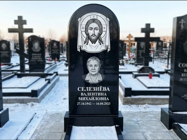 Памятник с гравировкой иконы: небольшая скромная одиночная стела с именной иконой — золочёный нимб на образе, аккуратный участок с газоном, работа «Ковалёв» в Санкт-Петербурге