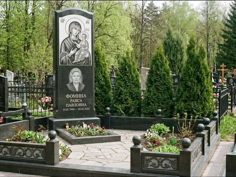 Памятник с гравировкой иконы: высокий гранёный обелиск с крестом-навершием — гравировка образа Матроны Московской, открытый участок без ограды, работа «Третьяков» в Санкт-Петербурге