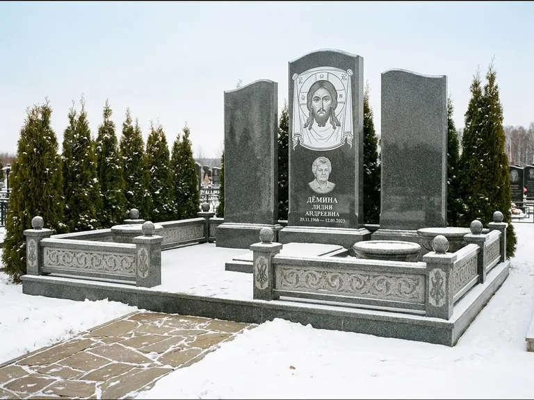 Памятник с гравировкой иконы: узкая вертикальная стела-пилон с ликом — икона в резной рамке-киоте, открытая лужайка без ограды, работа «Одинцов» в Санкт-Петербурге