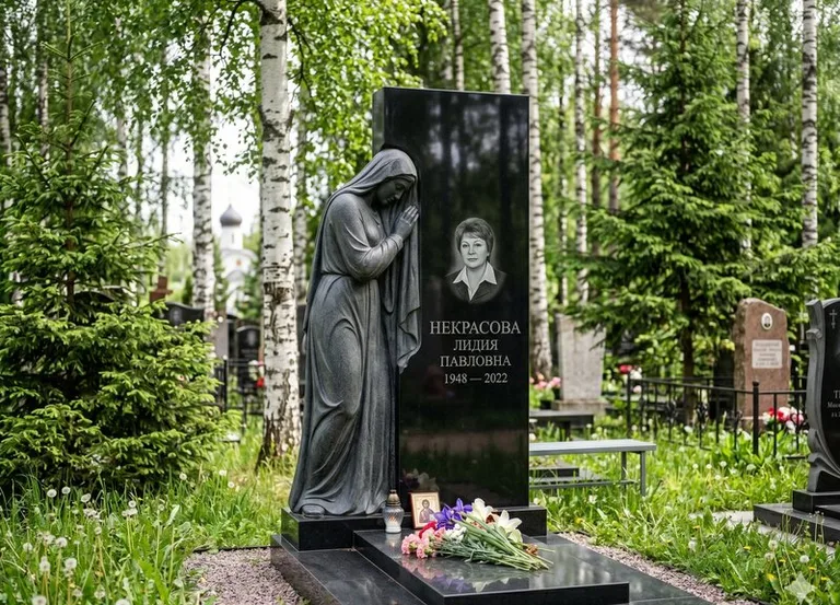 Гранитная фигура скорбящего мужчины у чёрной стелы в Санкт-Петербурге